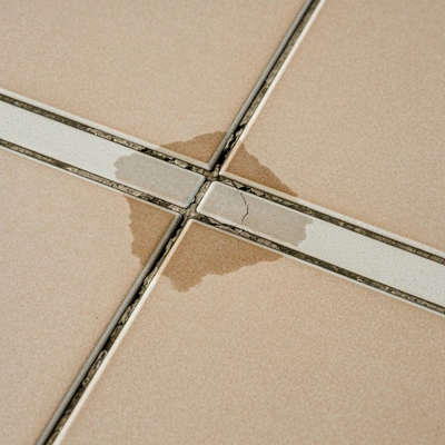 Detailed shot of a cracked balcony grout line with slight discoloration, indicating water damage